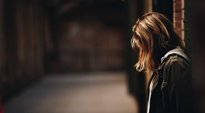 THE CLEANER WHO HATES MEN woman leaning against a wall in dim hallway