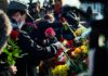 Mourners man in black suit holding bouquet of flowers