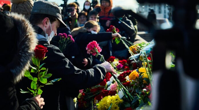 Mourners man in black suit holding bouquet of flowers