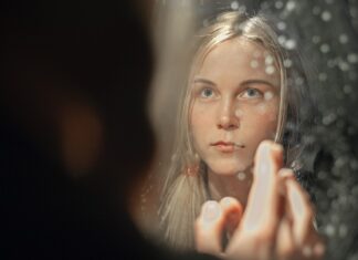 A Pretty Face woman with blonde hair holding her face