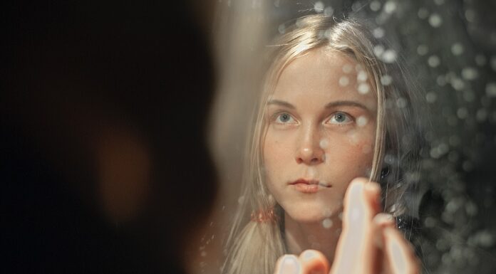 A Pretty Face woman with blonde hair holding her face