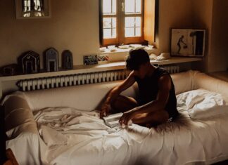 I CAN’T CALL YOU PAUL man sitting on bed beside opened window