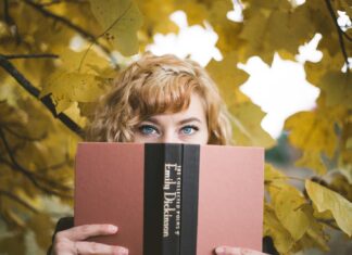 E. E. Dickinson selective focus photography of woman holding Emily Dickinson book
