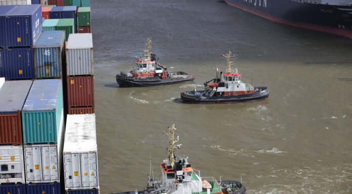River Angel cargo ships in front of piled intermodal containers
