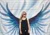 Icarus reincarnated woman taking photo near wings painted wall