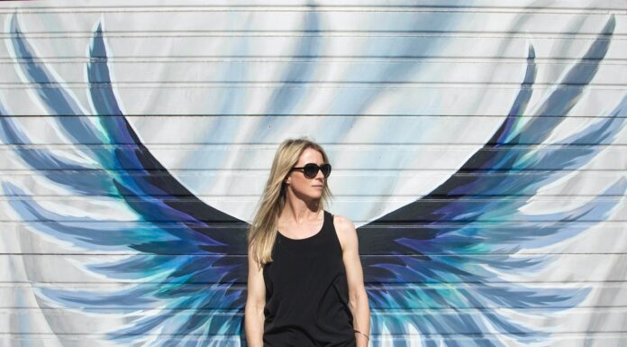 Icarus reincarnated woman taking photo near wings painted wall