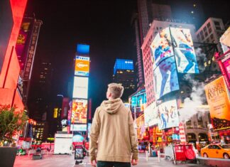 Signs man standing on road infront of high-rise buildi