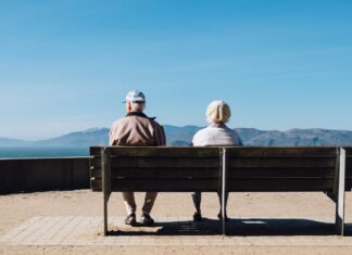 Empty Seat man and woman sitting on bench facing sea