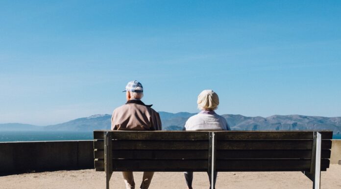 Empty Seat man and woman sitting on bench facing sea