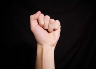 Pain of the sex persons left hand on black textile