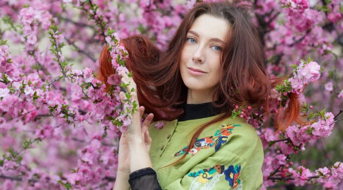 Big, Long, Red Hairs woman in green and yellow long sleeve shirt holding pink flowers