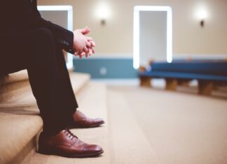 now that I’m old man in black pants and pair of brown leather lace-up shoes sitting on brown carpeted stairs inside room