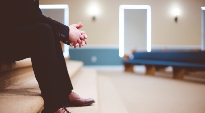 now that I’m old man in black pants and pair of brown leather lace-up shoes sitting on brown carpeted stairs inside room