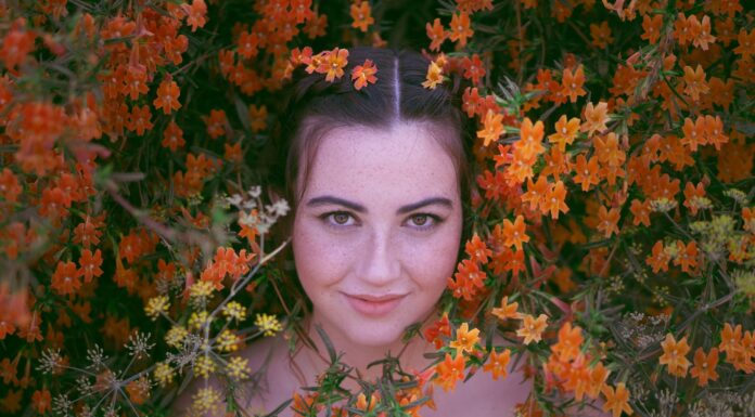A Bit of Breast Showing woman in black shirt surrounded by brown leaves