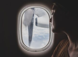 ~~ ~ woman wearing brown scoop-neck sitting near airplane window while sleeping during flight