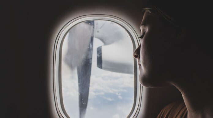 ~~ ~ woman wearing brown scoop-neck sitting near airplane window while sleeping during flight