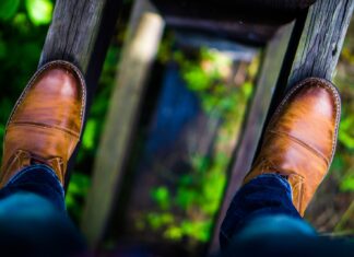 Addiction man wearing brown leather dress shoes stepping on brown wood