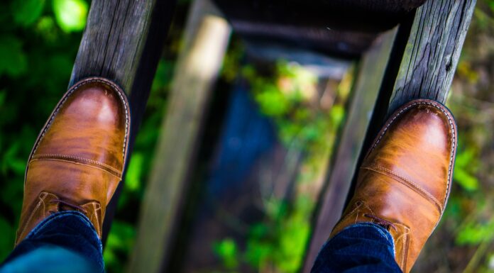 Addiction man wearing brown leather dress shoes stepping on brown wood