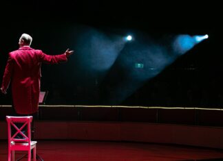the ringmaster never takes off his hat man in red coat