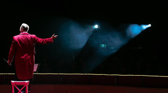 the ringmaster never takes off his hat man in red coat