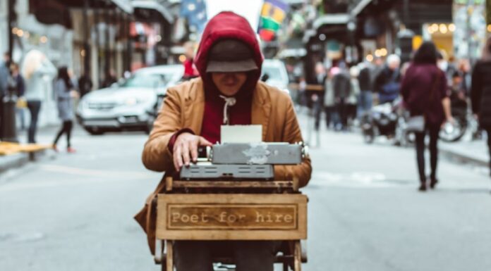 WHY YOU SHOULDN’T BE A POET man sitting on table typing on typewriter