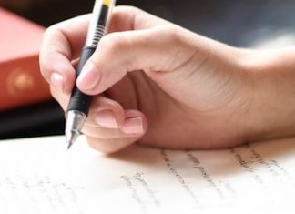 One Less Poem a person writing on a piece of paper with a pen
