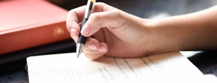 One Less Poem a person writing on a piece of paper with a pen