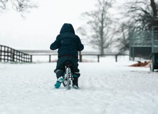 last of days person in black jacket and blue pants walking on snow covered ground during daytime