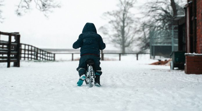last of days person in black jacket and blue pants walking on snow covered ground during daytime