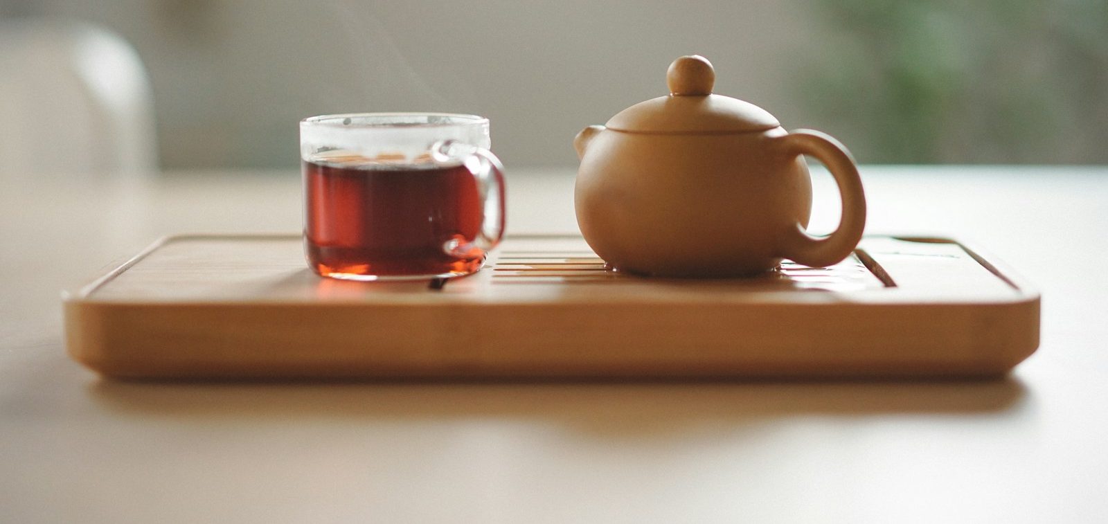 clear glass cup with tea near brown ceramic teapot