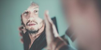 Visions selective focus photography of man's reflection on a broken mirror