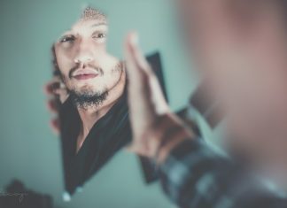 Visions selective focus photography of man's reflection on a broken mirror