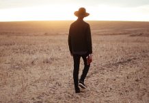 “I Once Was Lost…” man walking on dried plain while looking towards the sun on horizon