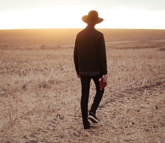 “I Once Was Lost…” man walking on dried plain while looking towards the sun on horizon