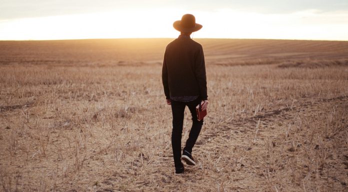 “I Once Was Lost…” man walking on dried plain while looking towards the sun on horizon