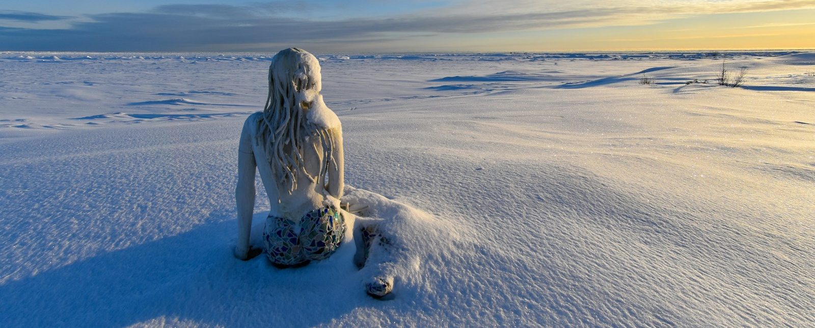 a statue of a woman sitting in the snow