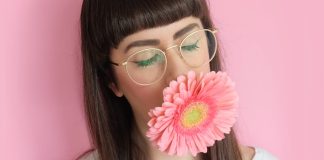 Bangs woman wearing eyeglasses with flower in mouth