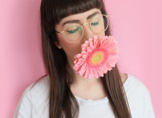 Bangs woman wearing eyeglasses with flower in mouth