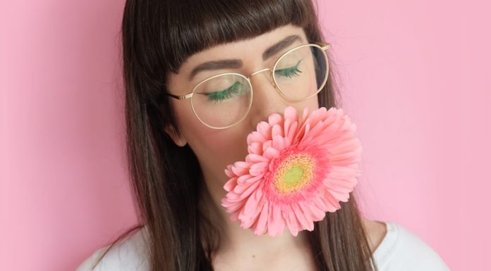 Bangs woman wearing eyeglasses with flower in mouth