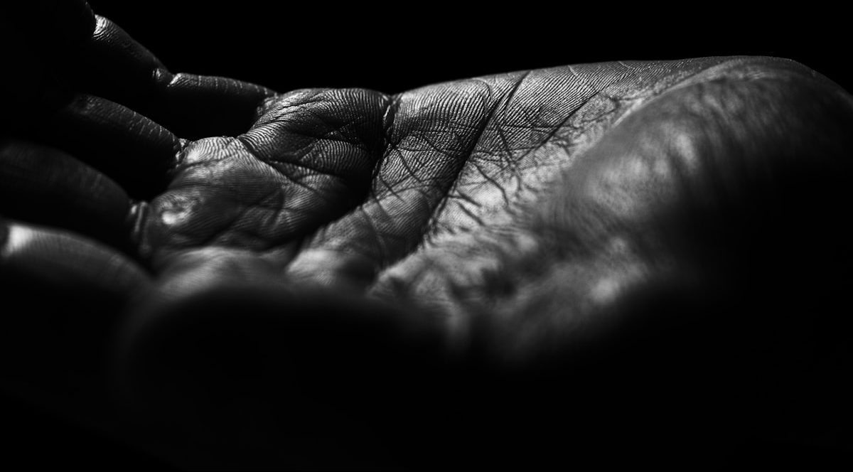 Close-up of a wrinkled hand against black background