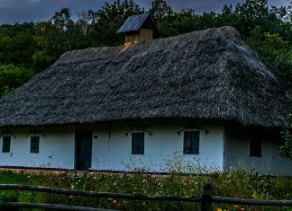 Clapham Rick a white house with a thatched roof and a wooden fence