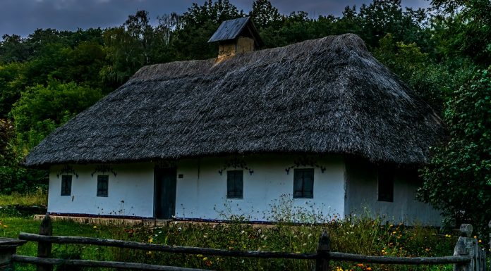 Clapham Rick a white house with a thatched roof and a wooden fence